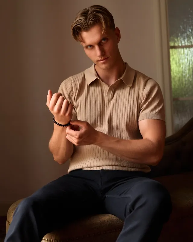 Portrait of Andrzej in beige polo shirt sitting on sofa in warm light, portrait session Wroclaw