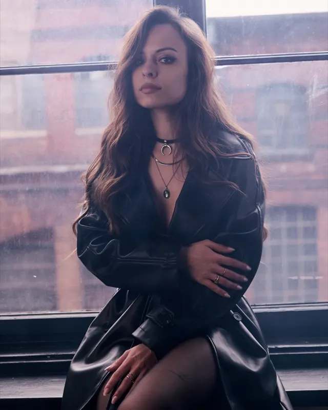 Angela w skórzanym płaszczu z chokerem przy industrialnym oknie, sesja portretowa Wrocław