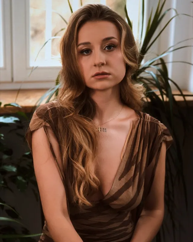 Sesja kobieca Wroclaw — Ala w brazowej bluzce przy oknie z roslinami, naturalne swiatlo, klimat apartamentu