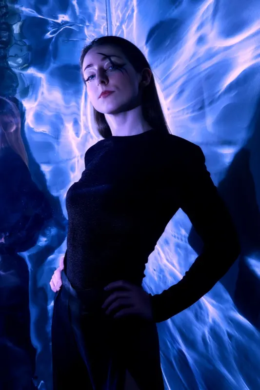 Ania in a black outfit against blue light projections, fashion session in Wrocław