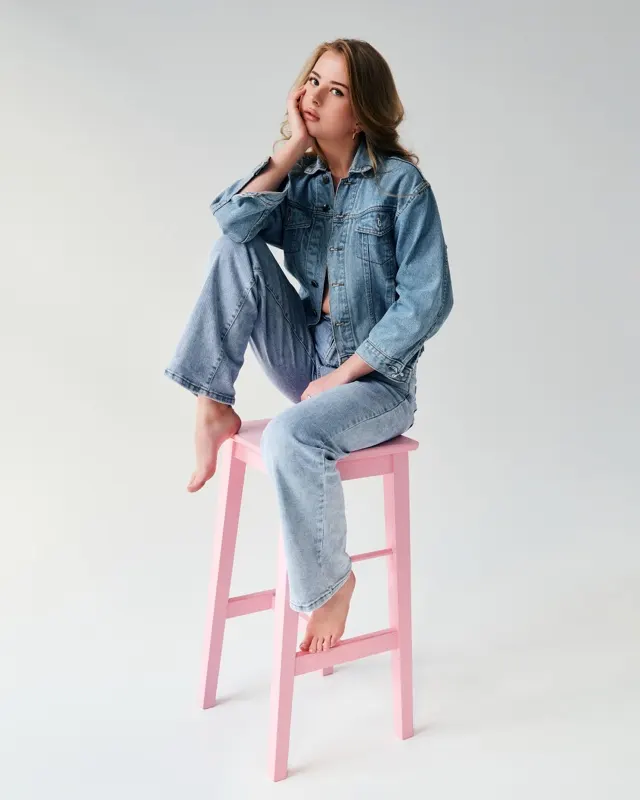 Laura in a full denim look sitting on a pink stool, fashion session in Wrocław