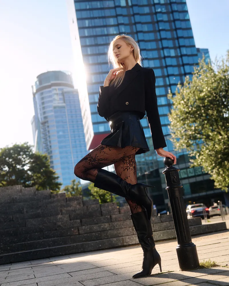 Nikola in a black blazer and short skirt with skyscrapers in the background, urban session