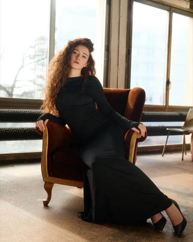 Salomea in a long black dress on a vintage armchair, fashion session in Warsaw