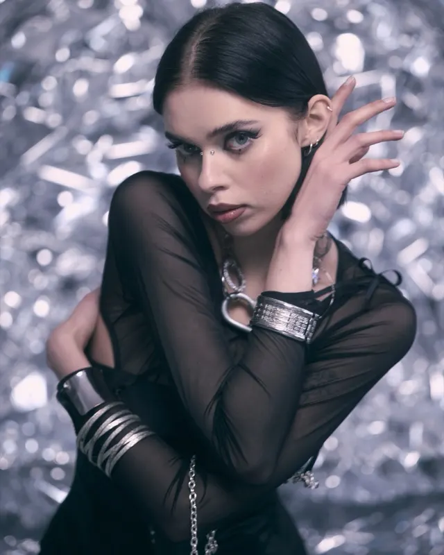 Wiola in a sheer black top with silver bracelets against a glittery backdrop, fashion session in Wrocław