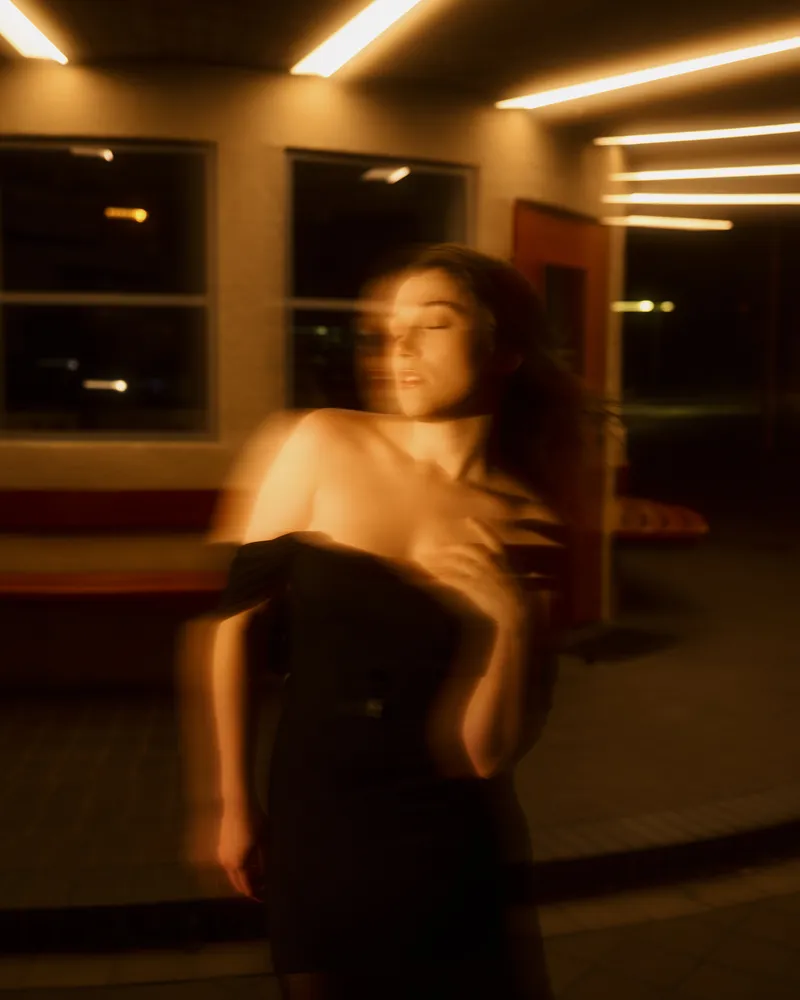 Wiktoria in a black dress, artistic portrait with motion blur and warm light